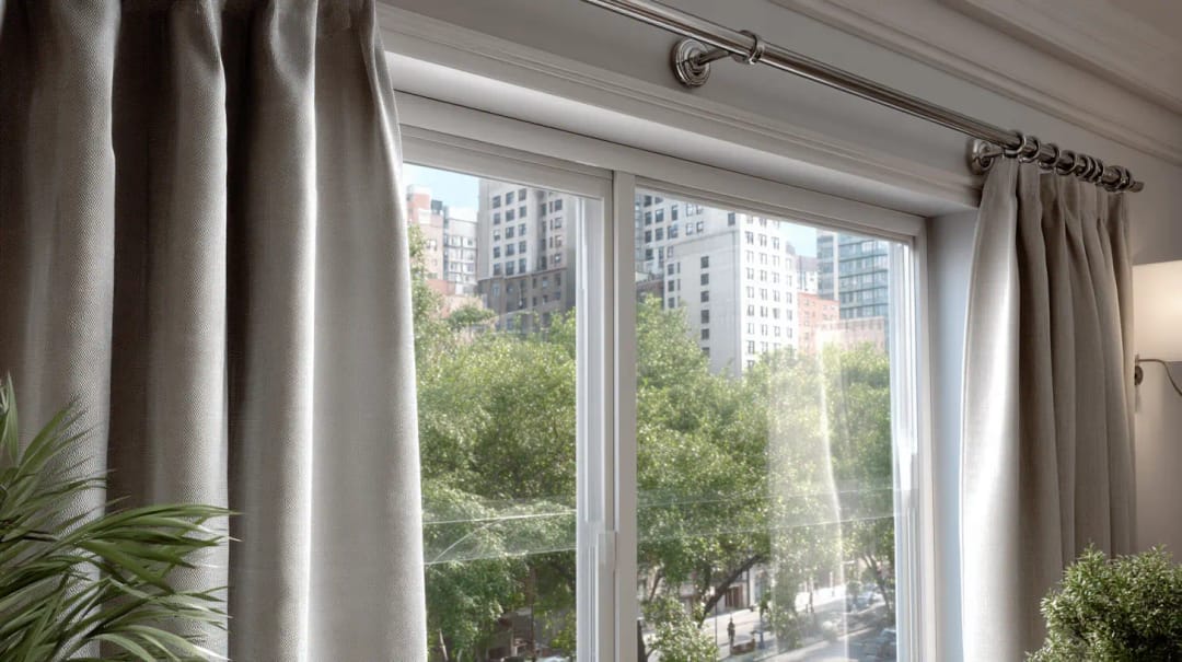 Chrome curtain rod on wall brackets above a window, with linen curtain panels